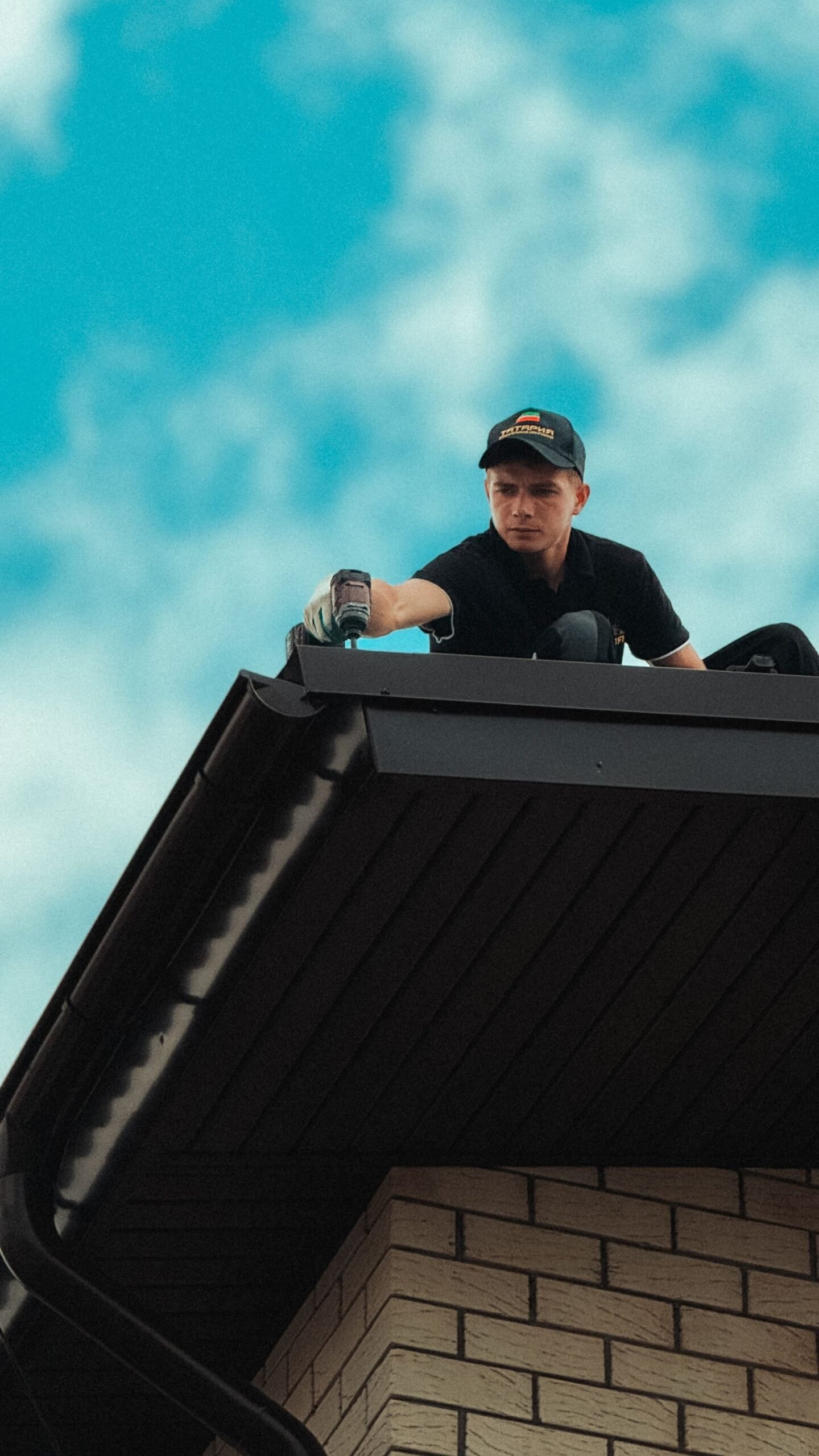 Dakdekker aan het werk op een dak onder een blauwe lucht