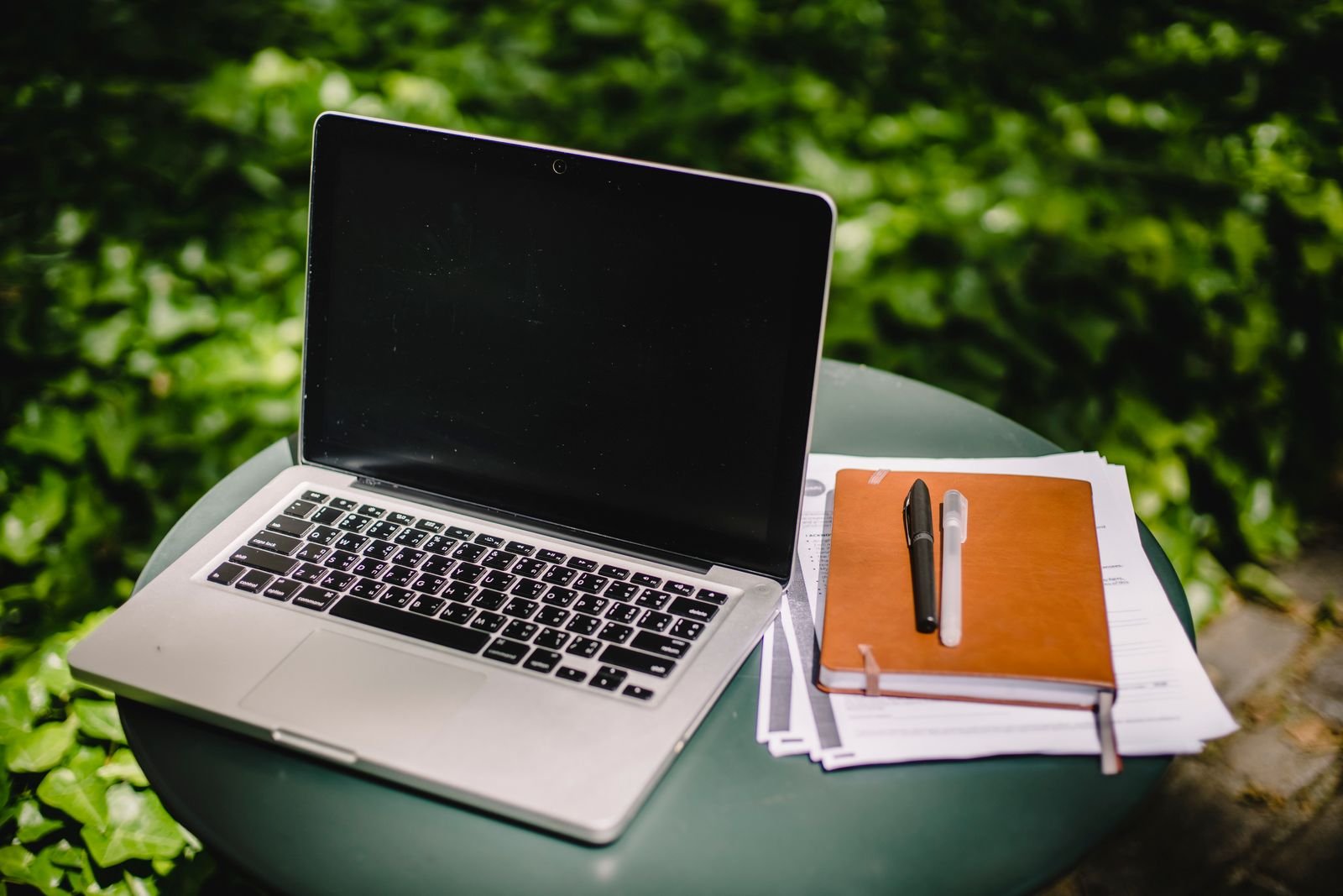 Laptop en notitieboek op een tafel in een groene tuin