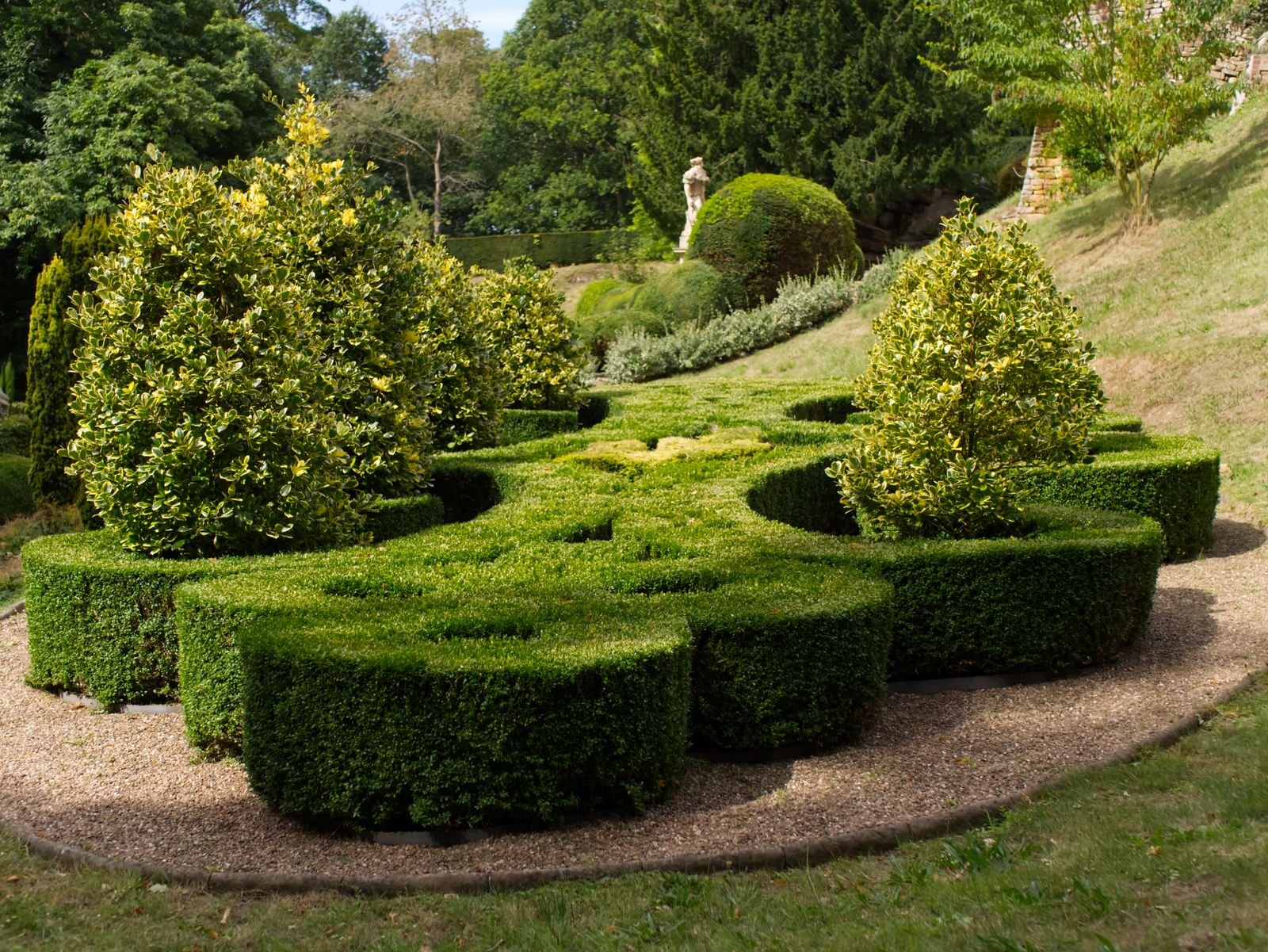 Tuin met gesnoeide buxus en vormsnoei langs een grindpad