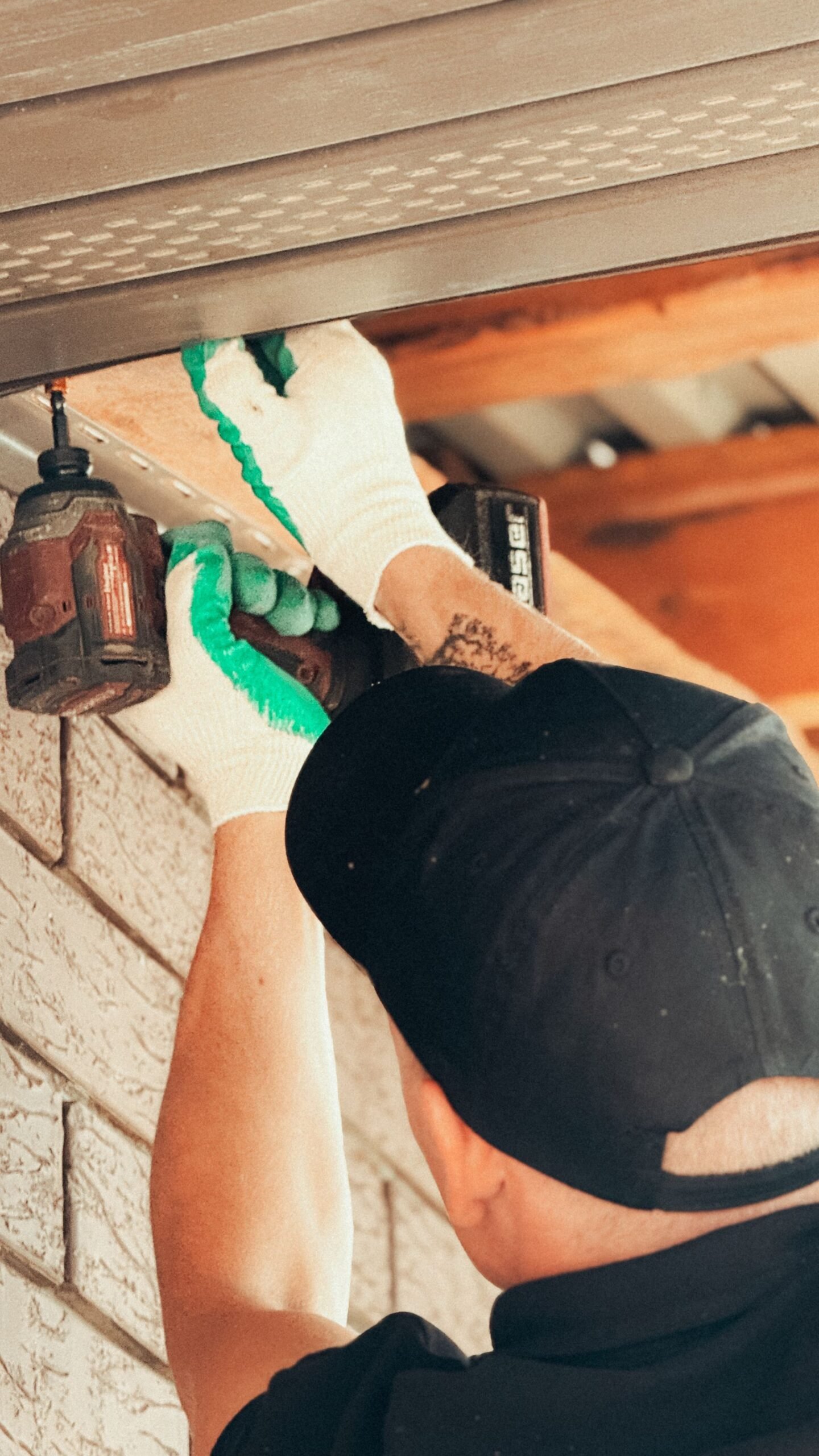 Vakman installeert buitenverlichting onder een dakrand
